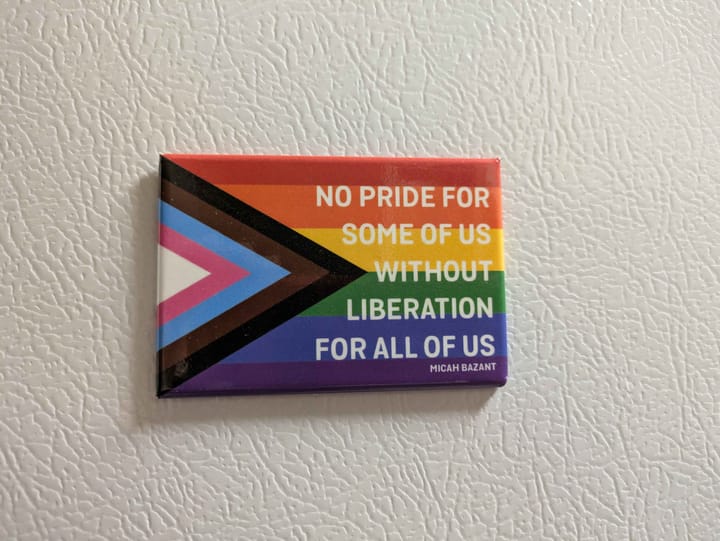 A magnet with the progress pride flag on it with the quote 'No pride for some of us without liberation for all of us.'